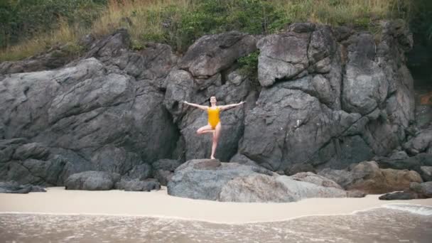 Mujer caucásica en traje amarillo practicando yoga ejercicio de fitness en la orilla del mar — Vídeos de Stock