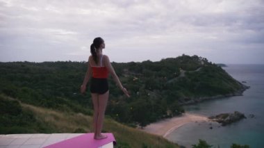 Kadın pratik yoga fitness egzersiz yüksek yere Adası'nın muhteşem manzaralı güneş doğarken