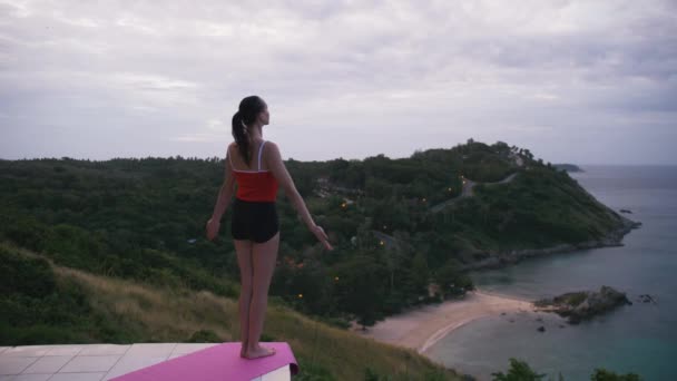 Γυναίκα εξάσκηση γιόγκα γυμναστικής άσκησης σε υψηλή θέση με καταπληκτική θέα του νησιού στο sunrise — Αρχείο Βίντεο