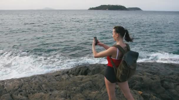 Vrouw reiziger bewonderen van uitzicht op zee en het maken van de foto op het strand met smartphone — Stockvideo