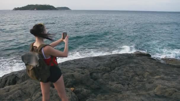 Viaggiatore donna ammirare la vista sul mare e fare foto sulla spiaggia con lo smartphone — Video Stock