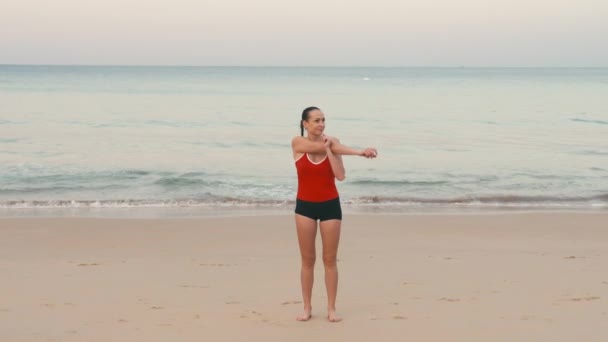 Giovane atleta maratona corridore in rosso riscaldamento sulla spiaggia tropicale prima dell'alba — Video Stock