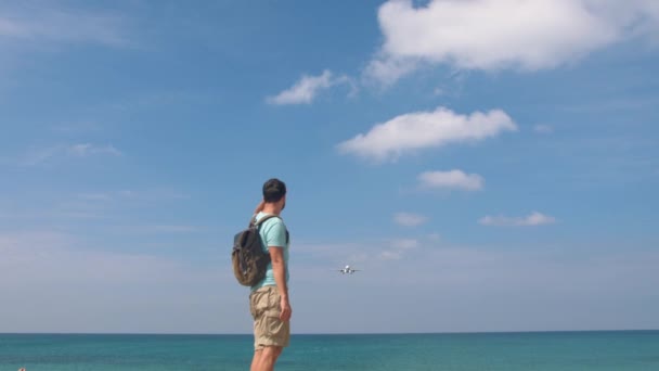 Tourist man with backpack welcomes airplane for travel. Hello vacation concept — Stock Video
