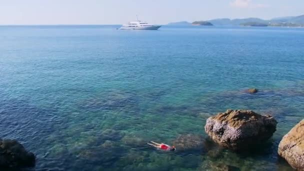 Giovane donna che fa snorkeling nell'acqua tropicale blu indossando costume da bagno rosso con nave da crociera all'orizzonte. Concetto di viaggio — Video Stock