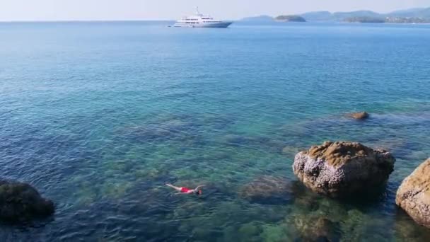 Ung kvinna snorkling i blå tropiska vatten bär röda baddräkt med kryssningsfartyg vid horisonten. Resor-konceptet — Stockvideo