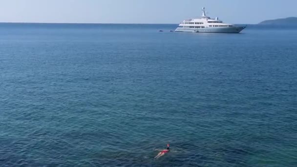 Giovane donna che fa snorkeling nell'acqua tropicale blu indossando costume da bagno rosso con nave da crociera all'orizzonte. Concetto di viaggio — Video Stock