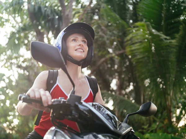 Mavi kask palmiye ağaçları ile orman yolda scooter motosiklet sürüş kadında. Tropikal seyahat ve motosiklet taşıma
