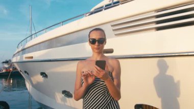 Marina iskele yatlar, arka plan ile onun smartphone kullanarak elbiseli şık Bayan