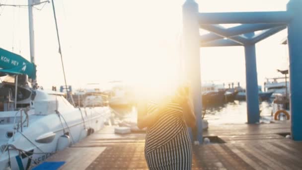 Edle Dame im Kleid mit ihrem Smartphone in Marina Pier mit Yachten im Hintergrund — Stockvideo