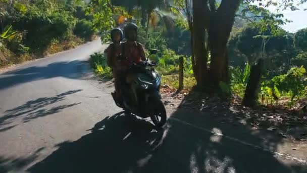 De jungle rijdt jonge mooie toeristische paar op een scooter dragen van helmen. Reizen, vrijheid, geluk, vakantie, huwelijksreis concept. — Stockvideo