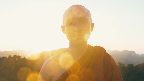 Krabi province, Thailand CIRCA 2019. Portrait of buddhist monk looking at camera with sunset sun in background — Stock Video