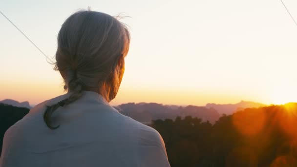 Achteraanzicht van onbestemde bejaarde vrouw met grijze haren waching zonsondergang op een zomeravond — Stockvideo