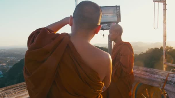 Province de Krabi, Thaïlande CIRCA 2019. Les moines bouddhistes font des photos les uns des autres avec un smartphone près de la statue de Bouddha sur le dessus du temple de la grotte du Tigre — Video