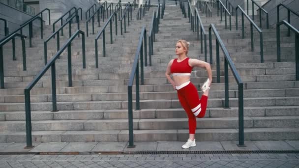 Плюс розмір змішаної раси блондинка усміхнена жінка в червоному спортивному одязі розігрівається перед бігом — стокове відео