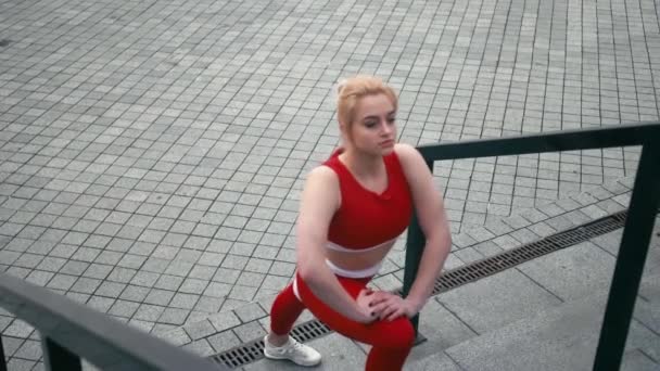 Plus storlek blandad ras blonda leende kvinna bär röda sportkläder värma upp innan kör — Stockvideo