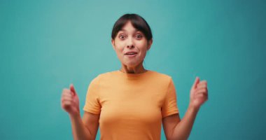 Heyecanlı İspanyol kadın mavi arka planda zafer çığlıklarını kutluyor. Genç Latin bayan, yavaş çekimde online piyango ikramiyesini kazandı.