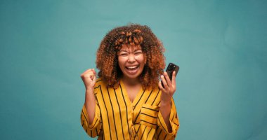 Şirin İspanyol genç kadın mavi arka planda at kuyruğu ipliğiyle oynaşıyor. Çekici Latin bayan yavaş çekimde şakacı bir şekilde gülümsüyor.