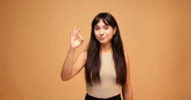 Mutlu İspanyol kadın ışıl ışıl ve kendine güvenerek gülümser ve mavi arka planda güzel bir jest yapar. Latin kadın mutluluk saçıyor. Yavaş çekim