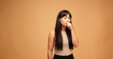 Stüdyoda mavi arka planda öksüren İspanyol kadın. Sağlık hizmeti, tıp konsepti