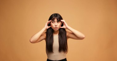 Mavi arka planda baş ağrısı hisseden genç İspanyol kadın. Acı çeken Latin bir kadın stüdyoda ağır çekimde duruyor.