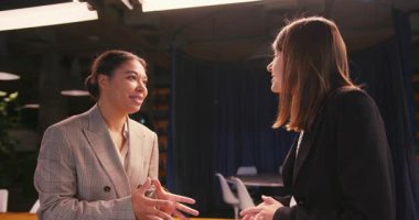 Takım elbiseli başarılı iş kadınları mükemmel iş sonuçlarını tartışıyor. Neşeli meslektaşlar güzel sonuçları kutlar ve karşılıklı beşlik çakarlar.