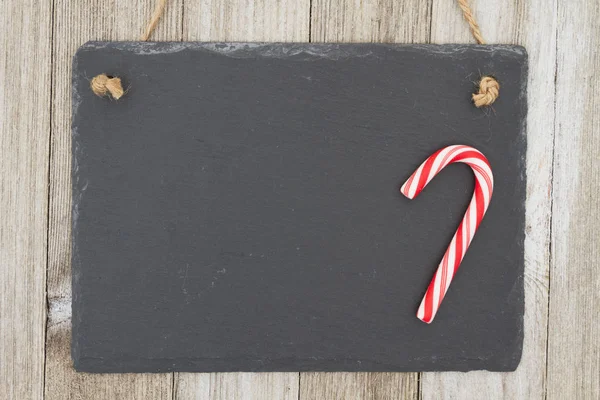 昔ながらのクリスマス吊り黒板背景 あなたのメッセージをコピー スペースと風化のウッドの背景に掛かっているキャンデー杖とレトロな黒板 — ストック写真