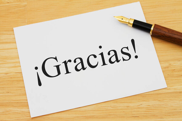 Spanish thank you message, A white card on a desk with a pen with text Gracias