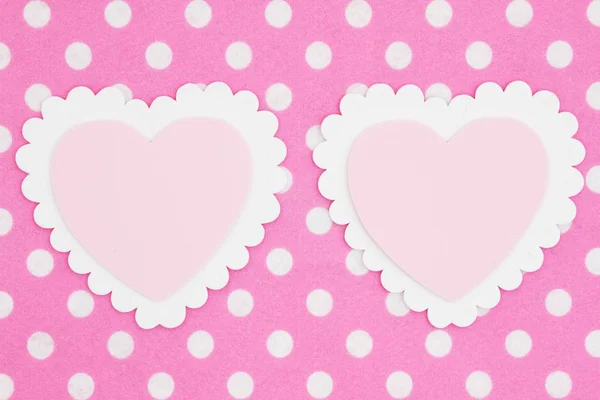 Two blank white and pink hearts on bright pink and white polka dot felt textured fabric background you can use the hearts for your message