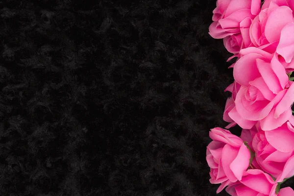 Pink roses on black rose textured plush fabric with copy space for your message