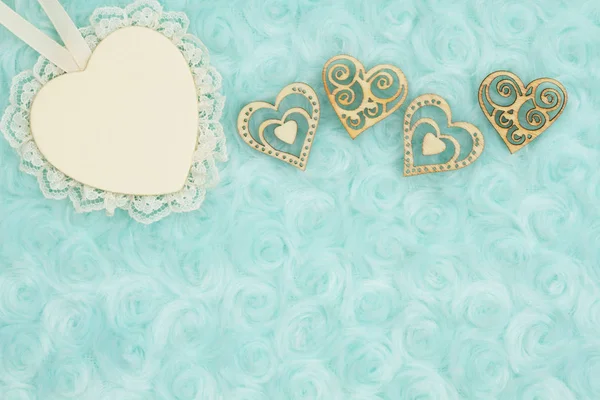 Wood heart with lace and wood hearts on pale teal rose plush fabric background with muted mix of shades to provide copy-space for your message