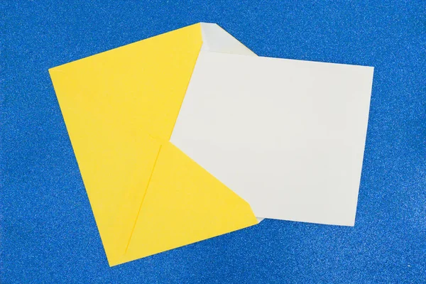 Busta gialla vuota con nota bianca bianca su blu — Foto Stock