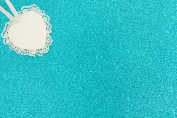 Wood heart with lace on bright teal glitter background