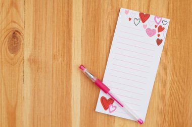 Kalp notepad ile ahşap bir masa üzerine kalem