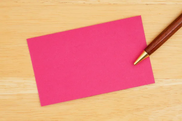 Rosa blank gratulationskort med pennan på texturerat trä bakgrund — Stockfoto