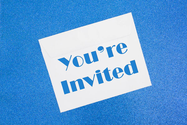 You 're Invited message on white envelope on blue
