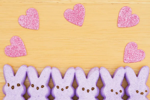 Fialový candy Zajíčci s růžové srdce na texturou dřeva poza — Stock fotografie