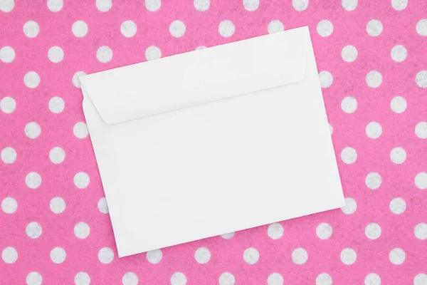 Pembe ve beyaz puantiyeli kumaş üzerine boş beyaz zarf — Stok fotoğraf