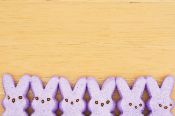 Purple candy bunnies on textured wood background — Stock Photo, Image