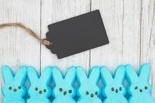 Синие конфеты кролики с подарочной биркой на выветренной белоснежной текстуре — стоковое фото