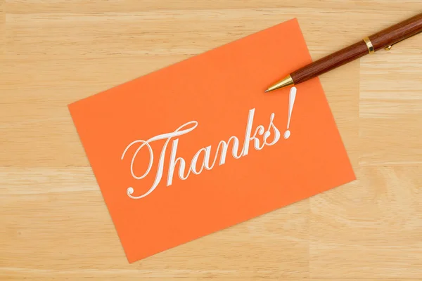 Obrigado cartão laranja com uma caneta em madeira texturizada — Fotografia de Stock