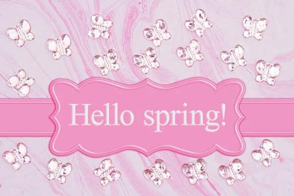 Olá mensagem de primavera com borboletas de vidro rosa na água rosa — Fotografia de Stock