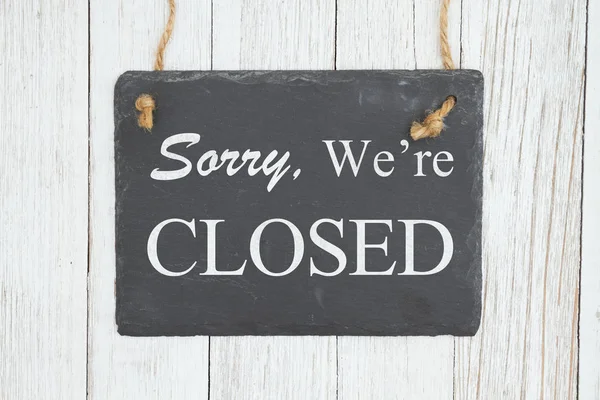 Sorry we're Closed text on a hanging chalkboard on weathered whi — Stock Photo, Image