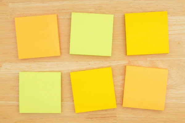 Six blank sticky notes on textured desk wood background