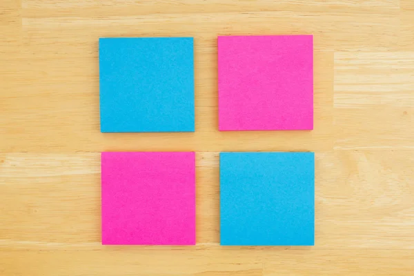 Quatro notas pegajosas em branco sobre fundo de madeira de mesa texturizada — Fotografia de Stock