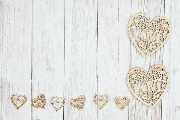 Дерев'яні серця на вивітрюваному побілки текстурованого дерев'яного фону — стокове фото