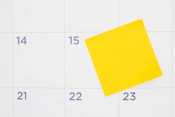 Blank yellow sticky note on a calendar