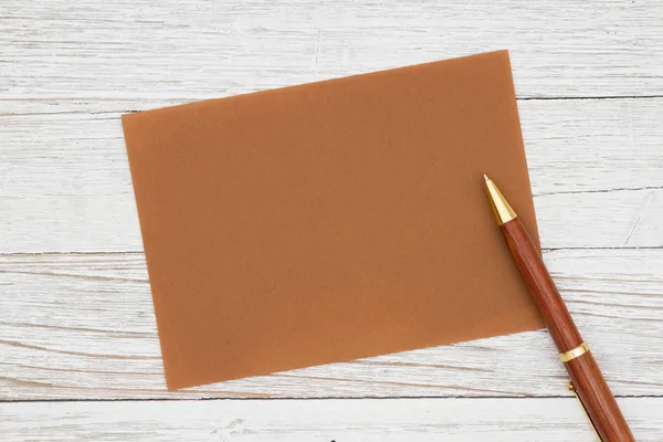 Порожня коричнева вітальна листівка з ручкою на вивітреній побіленій деревині — стокове фото