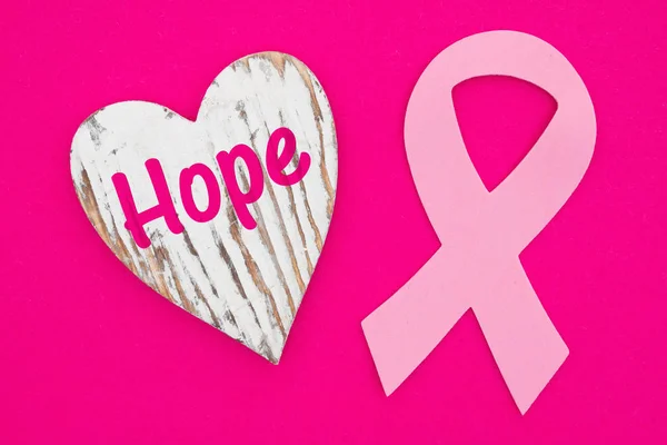 Hope message on weathered heart with pink cancer ribbon on brigh