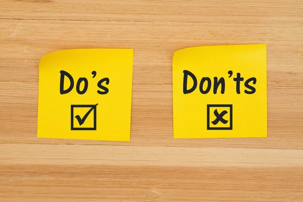 Do 's and Don' ts on two sticky notes on texured wood desk — Stock fotografie