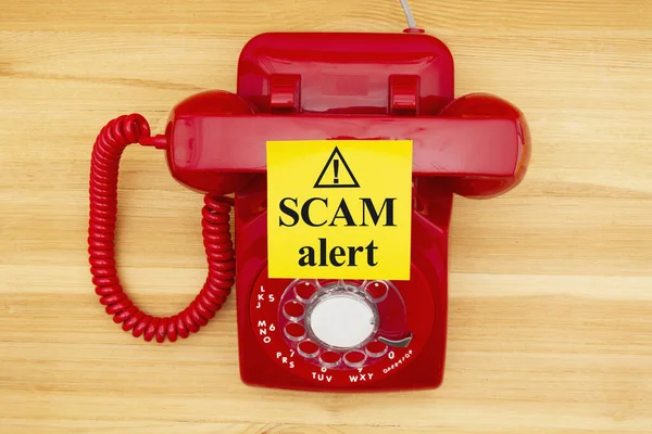 Scam alert message on a sticky note on a red old retro rotary ph — Stock Photo, Image